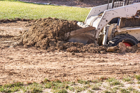 A tractor performing a grading work on a yard in southern Arizona