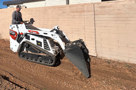 A worker from Hercs Works cleaning a yard, preparing it for construction in Southern Arizona
